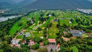 An aerial view of a golf course with multiple greens, bunkers, and water hazards. - Hotel Valley Vista (Visakhapatnam)