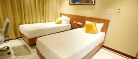 A hotel room with two single beds, a wooden headboard, a painting on the wall, and a curtain.