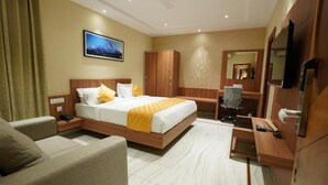 A hotel room with a bed, a sofa, a desk, a wardrobe, and a television. - Hotel Valley Vista (Visakhapatnam)