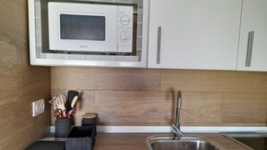 Una cocina moderna con microondas integrado, pileta de acero inoxidable y protector antibarrotes de madera.