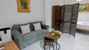 A modern living room with a grey sofa, a small round table with a plant, and a wooden partition.