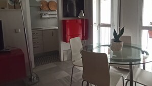 A modern kitchen with white cabinets, a red appliance, and a glass dining table with chairs. - Duplex with Private Terrace in Seville Center (Sevilla)