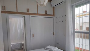 A bedroom with a bed, a wardrobe, and a window with a view of a building. - Duplex with Private Terrace in Seville Center (Sevilla)
