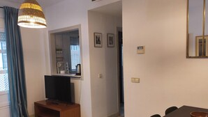 Un soggiorno con TV, tavolino in legno e zona pranzo con tavolo e sedie.