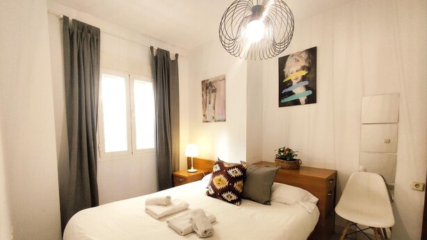 Una camera d'albergo con un letto, una scrivania, una sedia, una lampada e un quadro appeso al muro.
