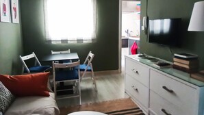 Ein gemütlicher Wohnraum mit Essbereich, einer Couch, einem Fernseher und einer Küchenzeile.