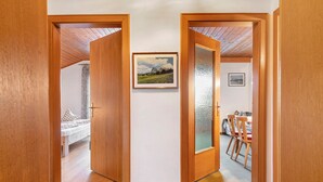 A hallway with wooden doors leading to a bedroom and a dining area.