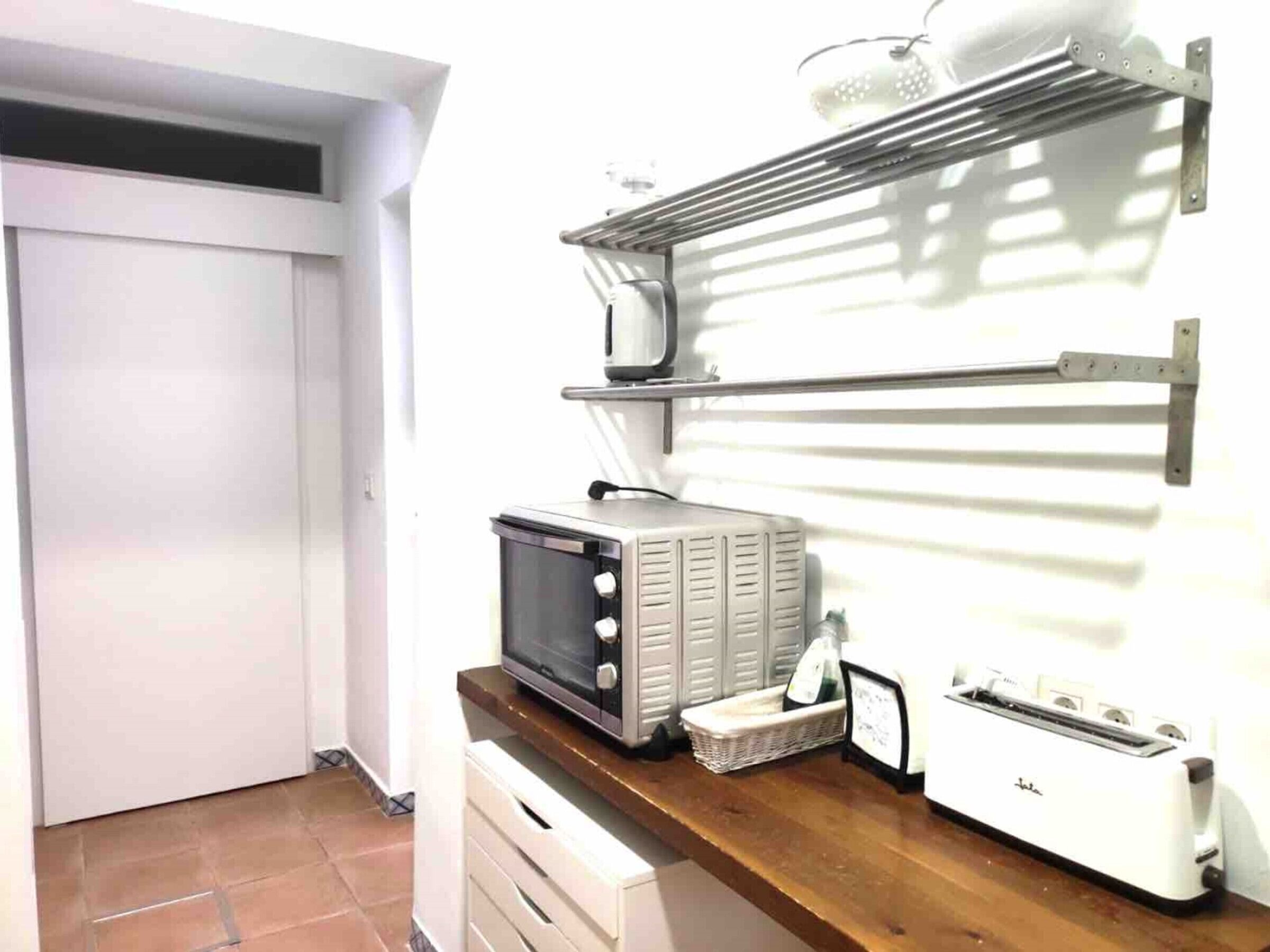 Cozinha equipada com micro-ondas, torradeira e um porta-roupas.