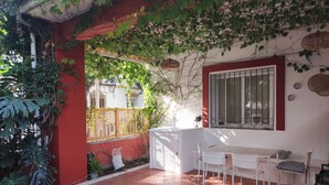 A patio area with a white table and chairs, a window with bars, and a red wall. - Accessible house in Triana with private patio (Sevilla)