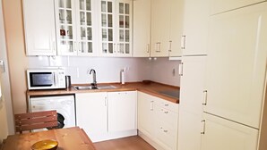 A compact kitchen with white cabinets, a microwave, a sink, and a washing machine.