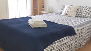A bedroom with a bed, a bedside table, a lamp, and a wardrobe.