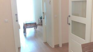 A hallway with a table and chairs, a door with frosted glass panels, and a light switch on the wall.