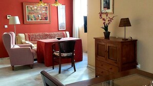 A living room with a red wall, a sofa, a dining table, and a cabinet.