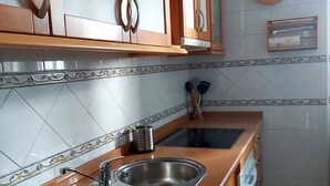 A kitchen with two stainless steel sinks, wooden cabinets, and a tiled backsplash.