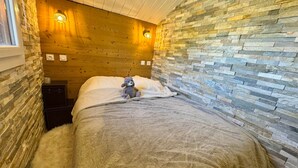 Un dormitorio acogedor con pared de piedra, techo de madera y una cama lujosa.