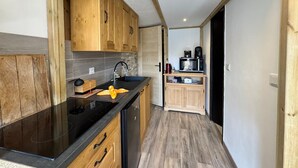 Cocina compacta con armarios de madera, encimera negra y horno empotrado.