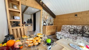 Interior acogedor de una cabaña con una mesa de comedor preparada para una comida, muebles de madera y vistas al exterior.