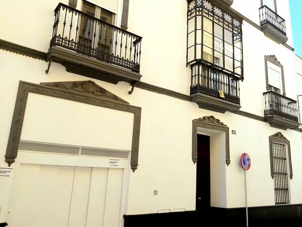 A building with ornate balconies, a large framed artwork, and a door marked with the number 65. - Quiet apartment in Seville center with parking (Sevilla)