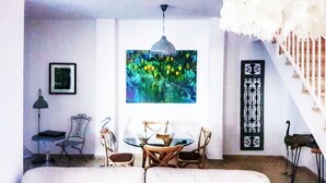 Un espace repas comprenant une table ronde, des chaises, un luminaire suspendu et un escalier.