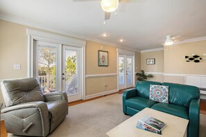 A living room with a leather armchair, teal sofa, and a coffee table with books. - Spacious 3BR Getaway with BBQ, close to Beach (North Myrtle Beach)
