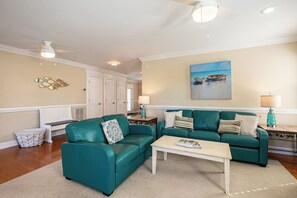 A living room with teal sofas, a coffee table, and a painting on the wall. - Spacious 3BR Getaway with BBQ, close to Beach (North Myrtle Beach)