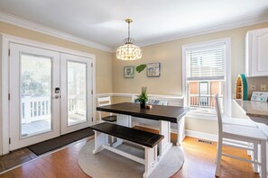 A dining area with a dark wooden table and bench, white cabinetry, and a hanging light fixture.