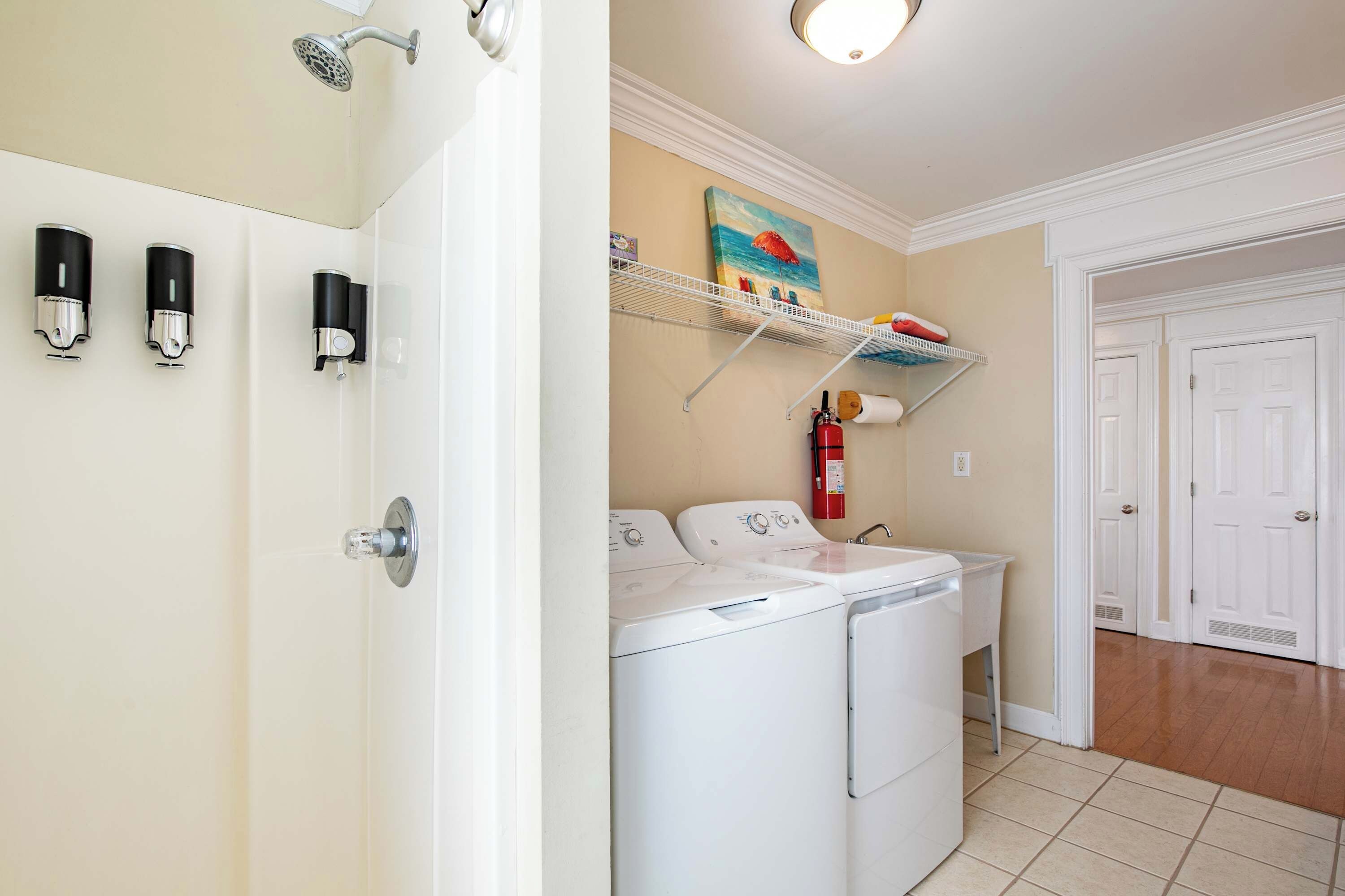 A laundry area with a washing machine and dryer, a shelf with towels, and a fire extinguisher.