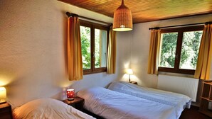 A room with two beds, a wooden ceiling, and windows with curtains. - 6-person apartment in quiet chalet near slopes (Le Grand-Bornand)