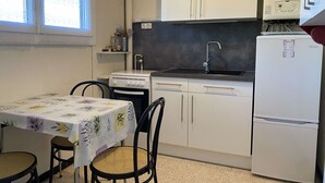 Une cuisine de taille réduite, avec des meubles blancs, un évier, une cuisinière et un réfrigérateur.
