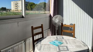 Une pièce avec une fenêtre, un ventilateur et une table recouverte d’une nappe à motifs.