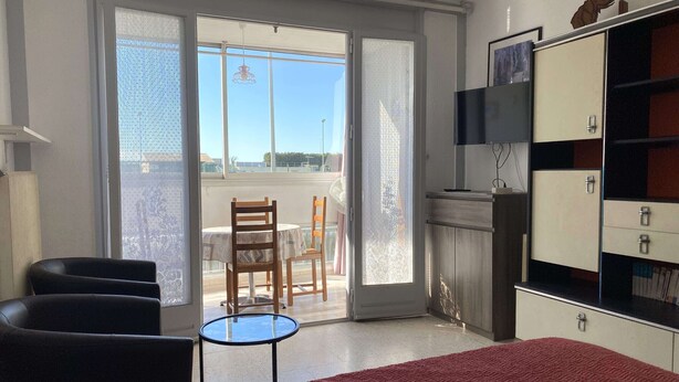 Une chambre d’hôtel avec un lit, une petite table, deux chaises, un téléviseur et une armoire.