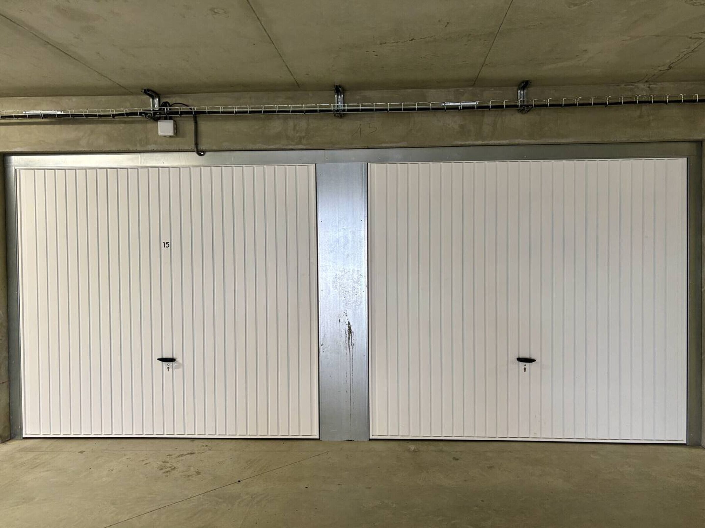 Een dubbele garagepoort met een metalen rails en een betonnen plafond.