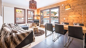 Un salon moderne comprenant un canapé, une table à manger, des chaises et un téléviseur.