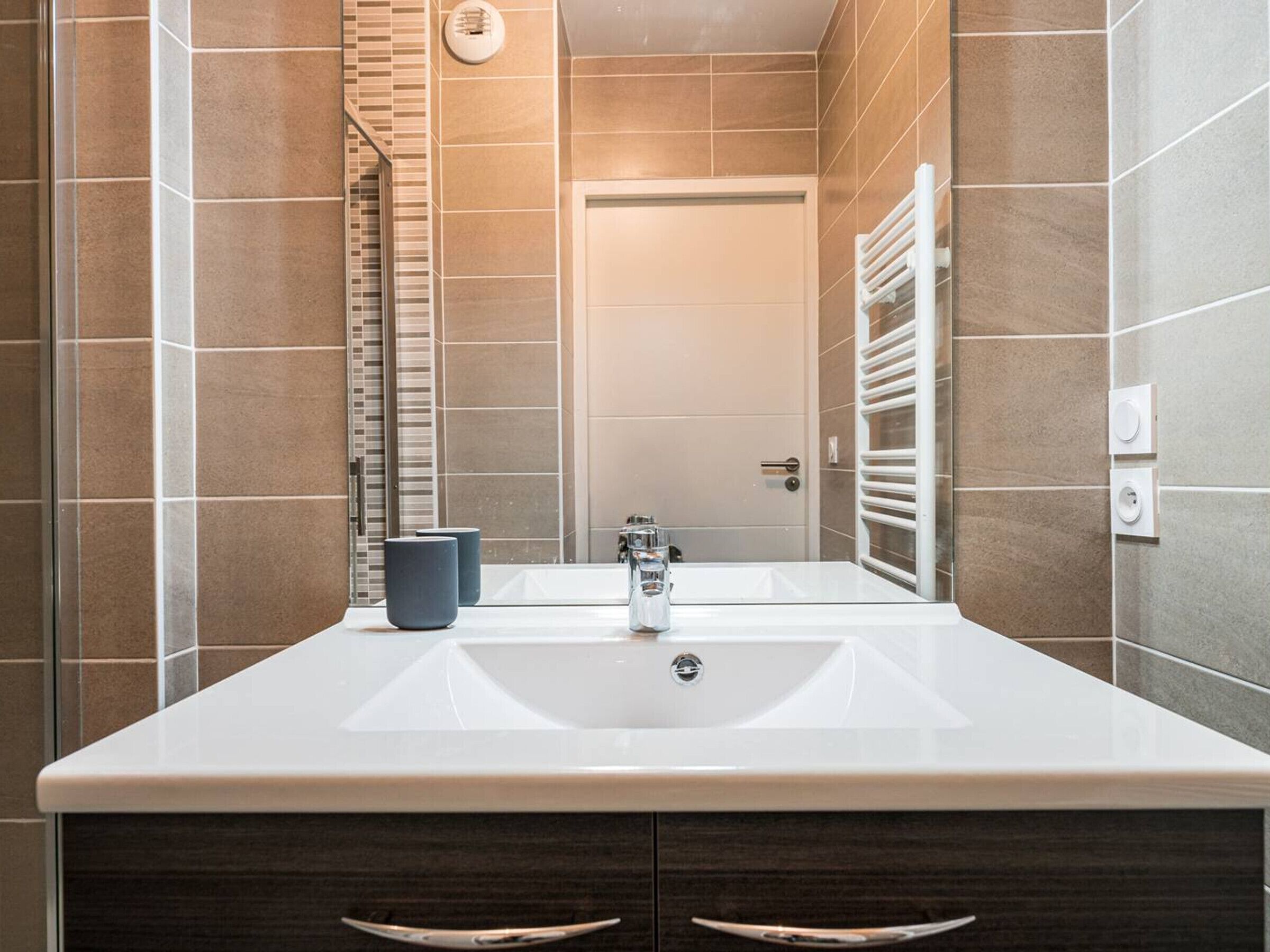 A modern bathroom with a large sink, a mirror, and a towel rack.