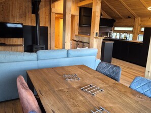 L’intérieur d’un chalet chaleureux, avec une table à manger en bois, un canapé et un coin cuisine.