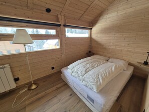 Quarto de cabana de madeira com cama, luminária de chão e janela.