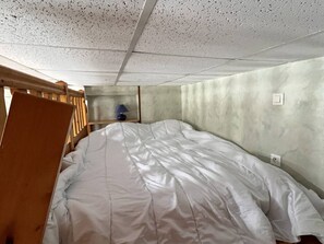 A room with a bed, a wooden chair, a nightstand, and a wall socket.