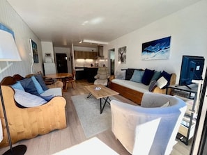 A modern living room with a sofa, armchairs, a coffee table, and a TV.