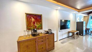A modern hotel room with a large painting, a television, a minibar, and a dining area with a view.