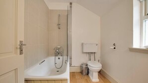 Een badkamer met een bad, toilet en een raam.