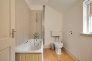 Une salle de bain avec une baignoire, des toilettes et une fenêtre.