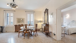 A room with a dining table, chairs, a chandelier, a bed, and a mirror. - Biennale Apartment 'A Short Walk' (Venezia)