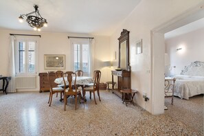 Una habitación con una mesa de comedor, sillas, una lámpara de araña, una cama y un espejo.