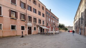 A paved square with buildings on either side, a row of outdoor tables and chairs, and a few people walking. - Biennale Apartment 'A Short Walk' (Venezia)