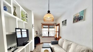 A living room with a TV, sofa, coffee table, and shelves with decorative items. - Apartment 'Rey Melchor' with Mountain View, Private Terrace and Wi-Fi (Trevélez)