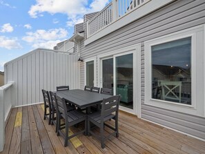 A deck with a table and chairs, a covered area, and a large window. - Seabatical - Pool next door - Ocean Views - 0.1 mi (Surf City)