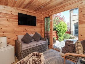 A cozy wooden cabin interior with a sofa, a television, and a wicker chair. - 127 Bellhouse Way (York)