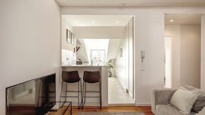A modern living room with a flat-screen TV, two bar stools, a grey sofa, and a wooden coffee table. - S O Bento Modern by Homing (Lisbon)