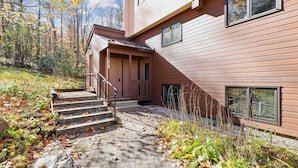 A modern two-story house with a wooden exterior, a covered porch, and a stone pathway leading to the entrance.