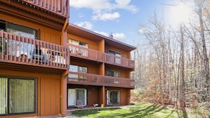 A multi-story building with balconies, large windows, and a grassy yard.